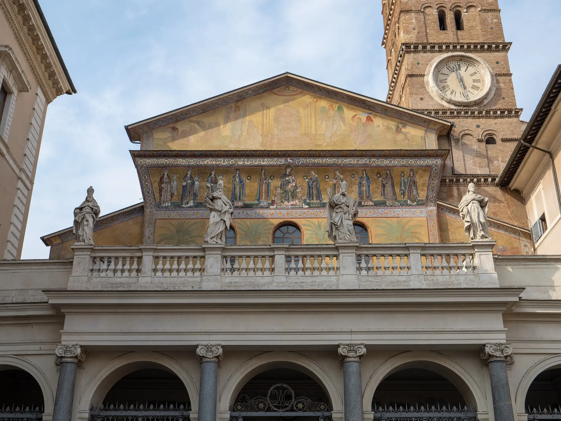 The facade of Santa Maria in Trastevere, with its gold mosaic frieze and bell tower.